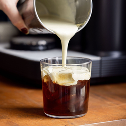 A close up of cold foam being poured on top of cold brew