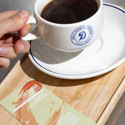 A close up of a cup of filter coffee on a board with a label next to it
