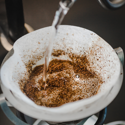 A close up of water being poured over coffee in a paper filter