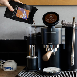 Pouring a bag of Dimattina Coffee into a Meraki espresso machine hopper