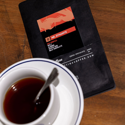 A close up of a bag of Mr. Dynamite coffee under a full cup of coffee