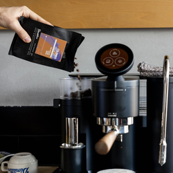 Pouring a bag of coffee into a Meraki hopper